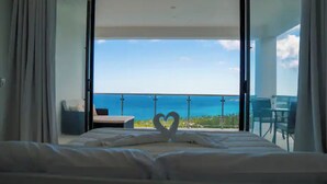 Une chambre d’hôtel avec un lit, une décoration en forme de cœur et un balcon offrant une vue sur l’océan.