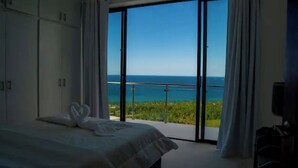 Une chambre avec un lit, une serviette en forme de cœur et un balcon avec vue sur la mer.
