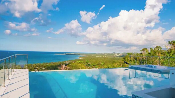 Une piscine à débordement offrant une vue dégagée sur l’océan et le paysage lointain.