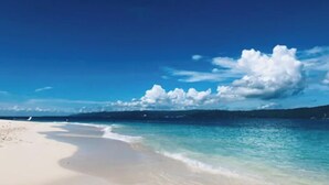 Une plage à l’eau turquoise et limpide et au sable blanc.