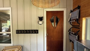 A room with a wooden door, a woven light fixture, a coat rack, a wicker chair, and a small rug. - FOX HILL All season retreat at Star Lake, Whiteshell with dock  (Star Lake)
