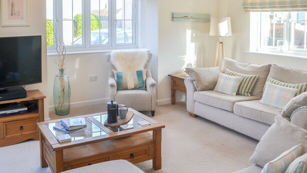 A living room with a sofa, armchair, coffee table, TV, and a lamp. - 3 bedroom accommodation in Beadnell (Beadnell)