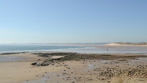 A wide beach with a rocky shoreline and distant mountains under a clear sky. - 3 bedroom accommodation in Beadnell (Beadnell)