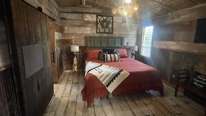 Una stanza rustica in legno con un letto, un lampadario e una finestra.