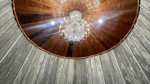 Un soffitto in legno circolare con un lampadario e una finestra a lucernario al centro.