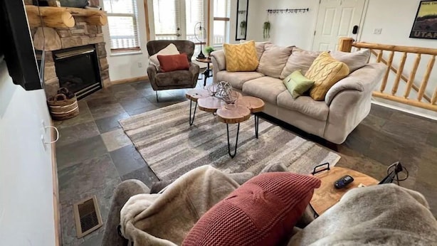 Ein Wohnzimmer mit Kamin, einer Couch, einem Sessel und einem Couchtisch.