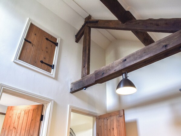 Een kamer met houten balken, een schuine plafond en een raam met luik.