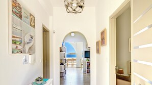 A hallway with a view of the sea, a bookshelf, and a dining area.