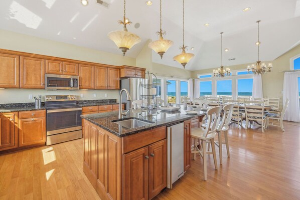 A spacious kitchen with wooden cabinets, stainless steel appliances, and a large island. - Premier Oceanfront Home w/ Pool, Hot Tub, Elevator, Putting Green, Game Room (Avon)