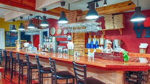 Een bar met een lange toonbank, meerdere hanglampen en een bord met een dessertmenu.