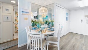 Un coin repas avec une table ronde, des chaises blanches et un lustre.