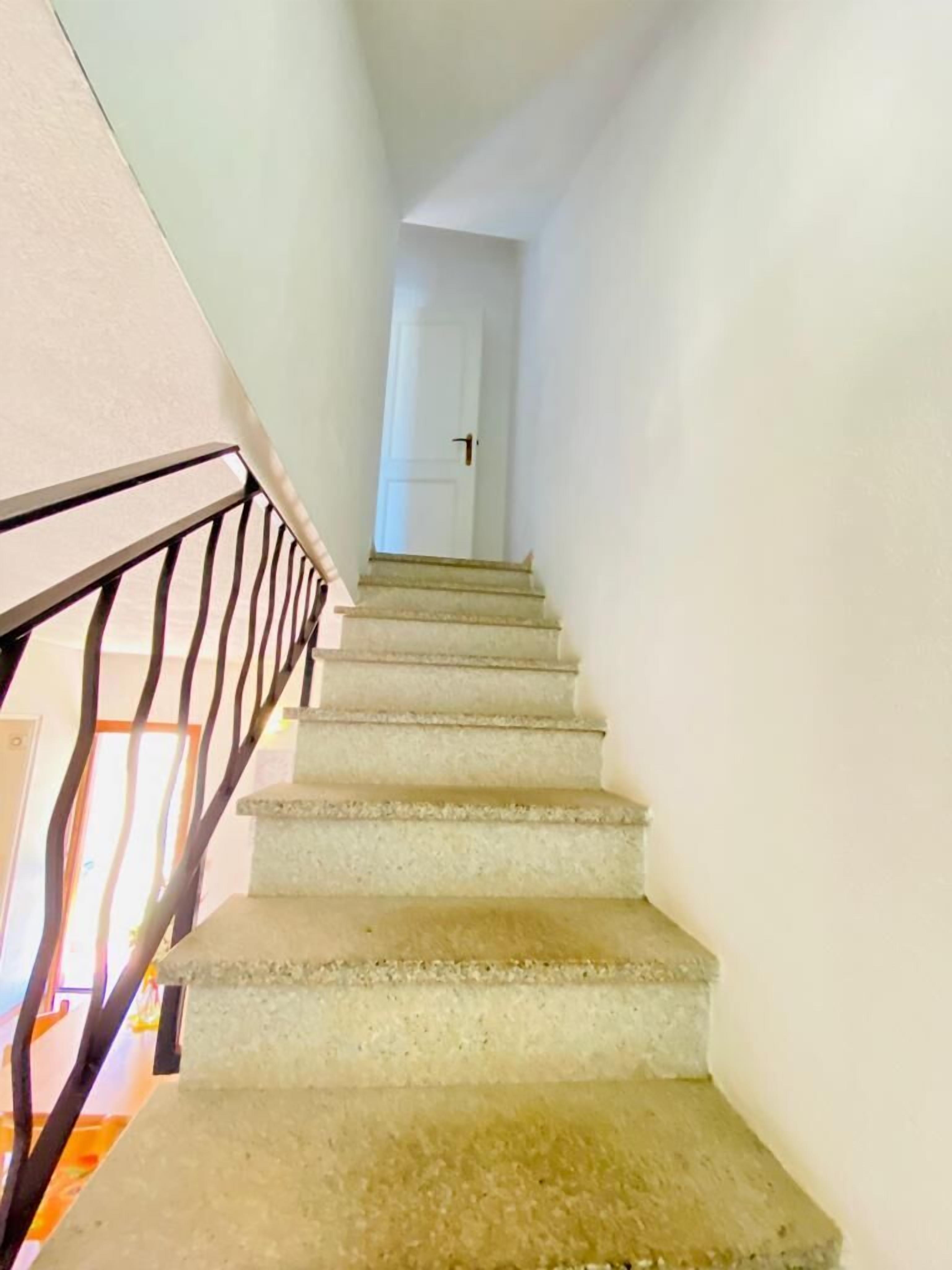 A staircase with a handrail, leading to a door at the top.