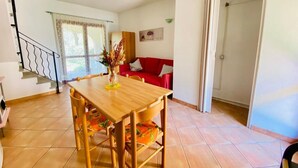 Un comedor con mesa y sillas de madera, un sofá rojo y una escalera.