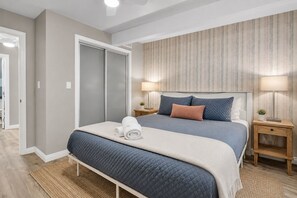 A bedroom with a bed, bedside tables, a wardrobe, and a view of the hallway. - Spacious Beach Home-Rooftop Deck-Steps to Sand (Oxnard)