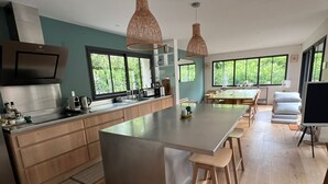 Une cuisine moderne dotée d’un grand îlot central, de meubles en bois et de luminaires suspendus.