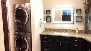 A laundry area with two stacked front-loading washers and dryers, a granite countertop with a sink, and a mirror above the countertop. - Lookout Mountain Lodge & Chalet with Views! (30 Day Min) (Golden)
