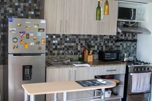 Une cuisine équipée d’un réfrigérateur, d’un four à micro-ondes, d’une cuisinière et d’un plan de travail recouvert de carreaux.