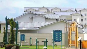 Un'area fitness all'aperto con attrezzi ginnici, un'area giochi per bambini e un edificio sullo sfondo.