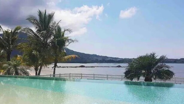 Una piscina limpida con vista su un'acqua calma e montagne in lontananza.