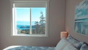 Un dormitorio con un amplio ventanal que ofrece vistas a un bosque y montañas.
