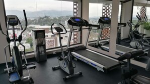 Una palestra con tapis roulant, ellittiche e un erogatore d'acqua.