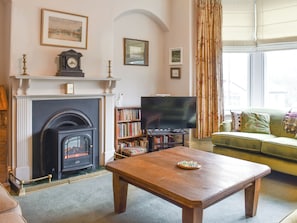 A living room with a fireplace, a television, a bookshelf, and a sofa.