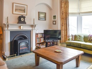 A living room with a fireplace, a television, a bookshelf, and a sofa. - 4 bedroom accommodation in Kirkby Lonsdale (Kirkby Lonsdale)
