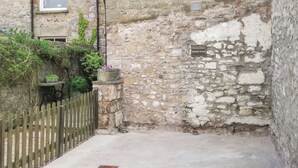 Un estrecho callejón de piedra con una valla de madera, una pequeña mesa y un cartel que indica estacionamiento privado en Hillside House.