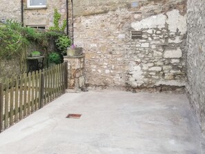 Un estrecho callejón de piedra con una valla de madera, una pequeña mesa y un cartel que indica estacionamiento privado en Hillside House.