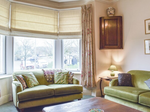 A room with a green sofa, a wooden coffee table, and a cabinet.