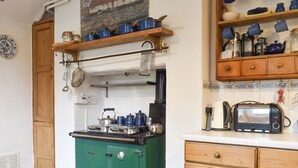 Eine Küche im Vintage-Stil mit einem grünen Herd, Holzschränken und einem Fliesenboden.
