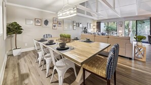 Een moderne eethoek met een houten tafel, witte stoelen en een hanglamp.