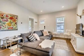 Relax in this stylish living room with a grey sofa, white armchair, and flat-screen TV.