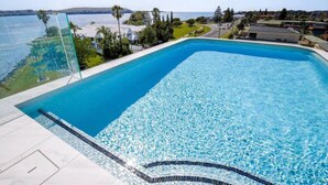 Une piscine rectangulaire à l’eau d’un bleu limpide, entourée d’une terrasse carrelée.