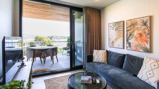 Un salon moderne avec un canapé, une table basse et un balcon agrémenté de meubles en osier.