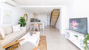 Ein modernes Wohnzimmer mit einer Couch, einem Couchtisch, einem Fernseher und einer Treppe, die zu einer oberen Etage führt.