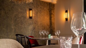 A dining area with a table set for four, two wall-mounted light fixtures, and a textured wall. - Boutique Hotel Four (Geldrop)