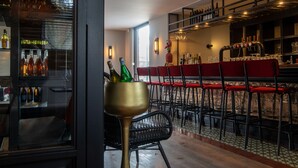 A bar area with a counter, shelves with bottles, and red bar stools. - Boutique Hotel Four (Geldrop)