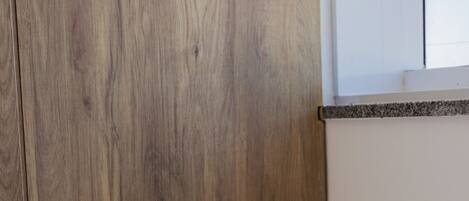 A bedside table with a lamp, a power outlet, and a remote control.