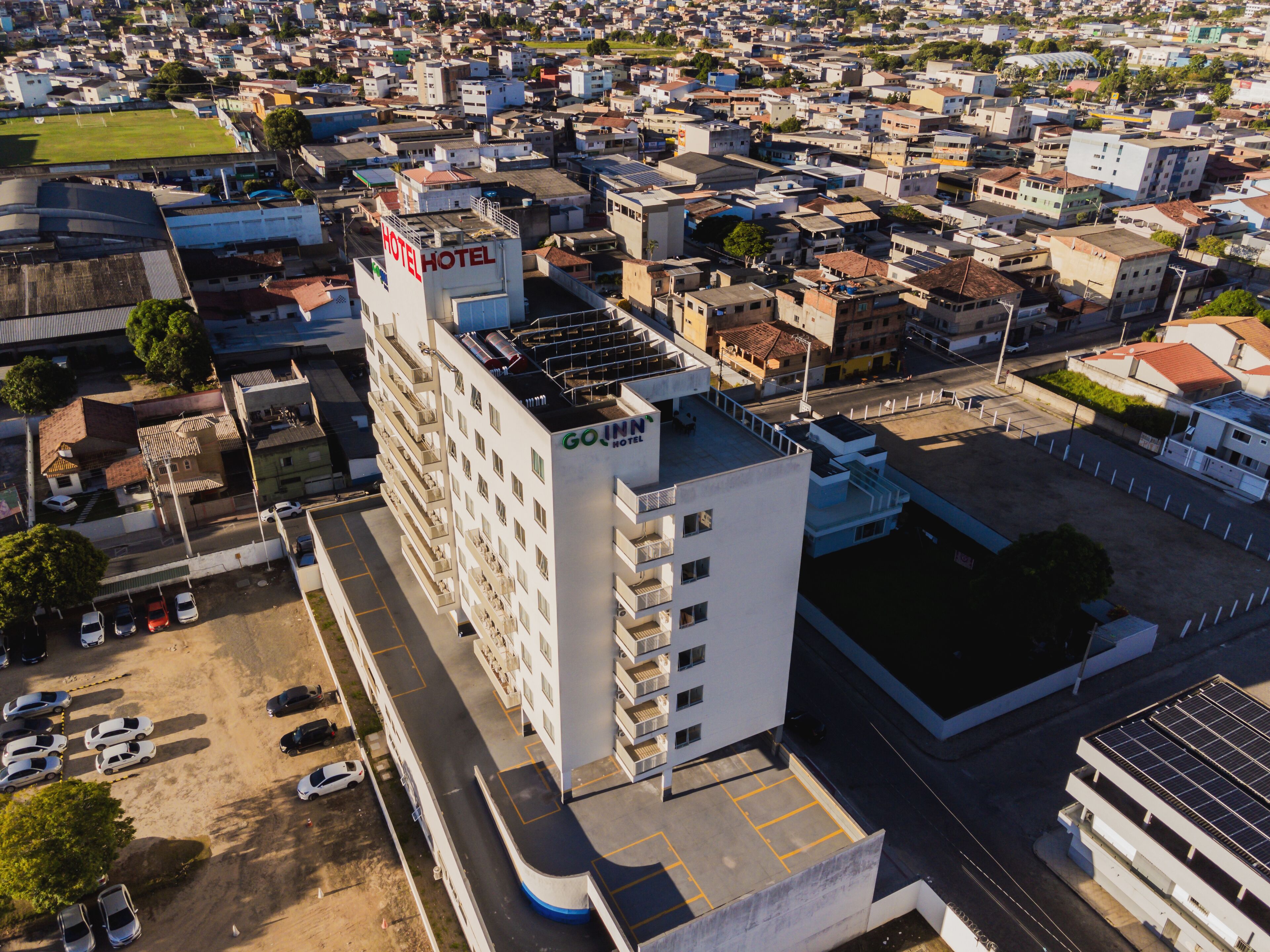 Un hôtel à plusieurs étages doté d’une terrasse sur le toit et d’un parking.