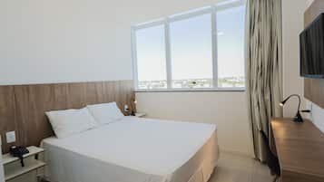 Ein Hotelzimmer mit Bett, Schreibtisch, Stuhl, Fernseher und Fenster mit Aussicht.
