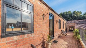 A brick building with large windows, a patio with a table and chairs, and a potted plant. - Betty Hutton - UK36661 (Belchford)