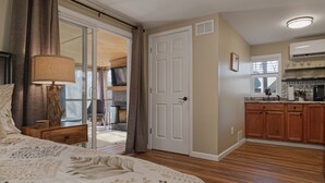 A bedroom with a large bed, a nightstand, a lamp, and a sliding glass door leading to a balcony. - Cozy Waterfront Escape near Helen & Vineyards (Cleveland)
