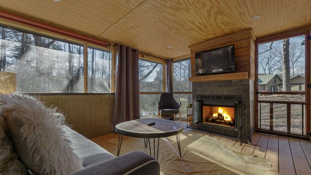A cozy living room with a fireplace, a sofa, a TV, and large windows. - Cozy Waterfront Escape near Helen & Vineyards (Cleveland)