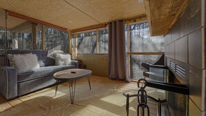 A modern living room with a sofa, a round coffee table, and a fireplace. - Cozy Waterfront Escape near Helen & Vineyards (Cleveland)