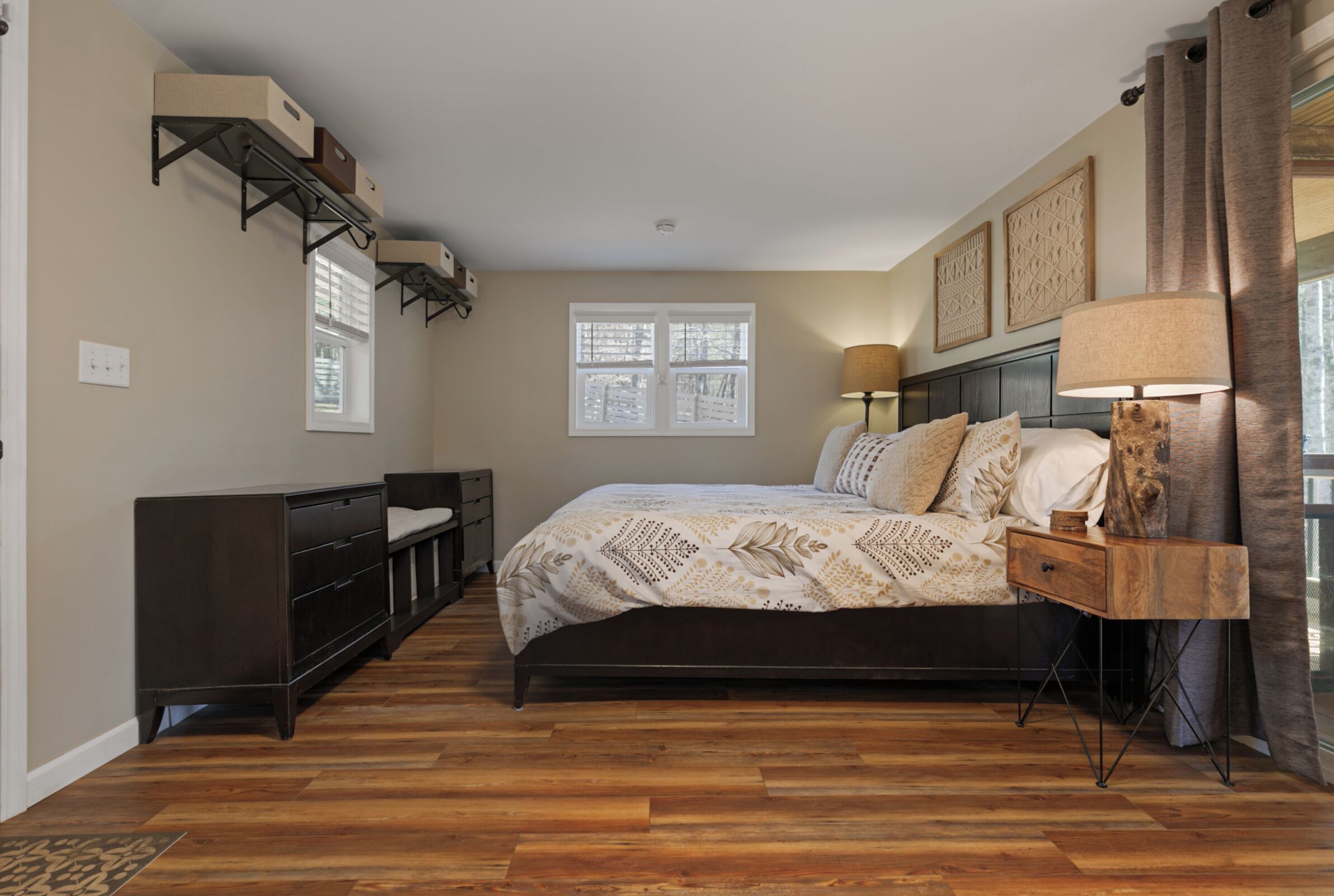 A bedroom with a bed, bedside lamps, a dresser, and a window.