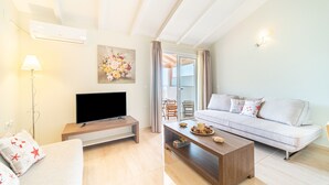 Ein modernes Wohnzimmer mit Flachbildfernseher, einer Couch, einem Couchtisch und einem Gemälde an der Wand.