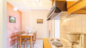Een keuken met een eettafel, stoelen, een koffieapparaat en uitzicht op buiten.