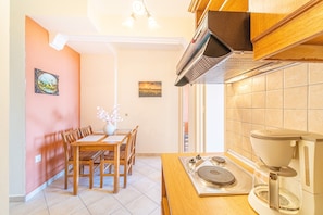 A kitchen with a dining table, chairs, a coffee machine, and a view of the outside.