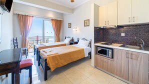 Une chambre d’hôtel avec deux lits, une table à manger, un coin cuisine et un balcon avec des rideaux.